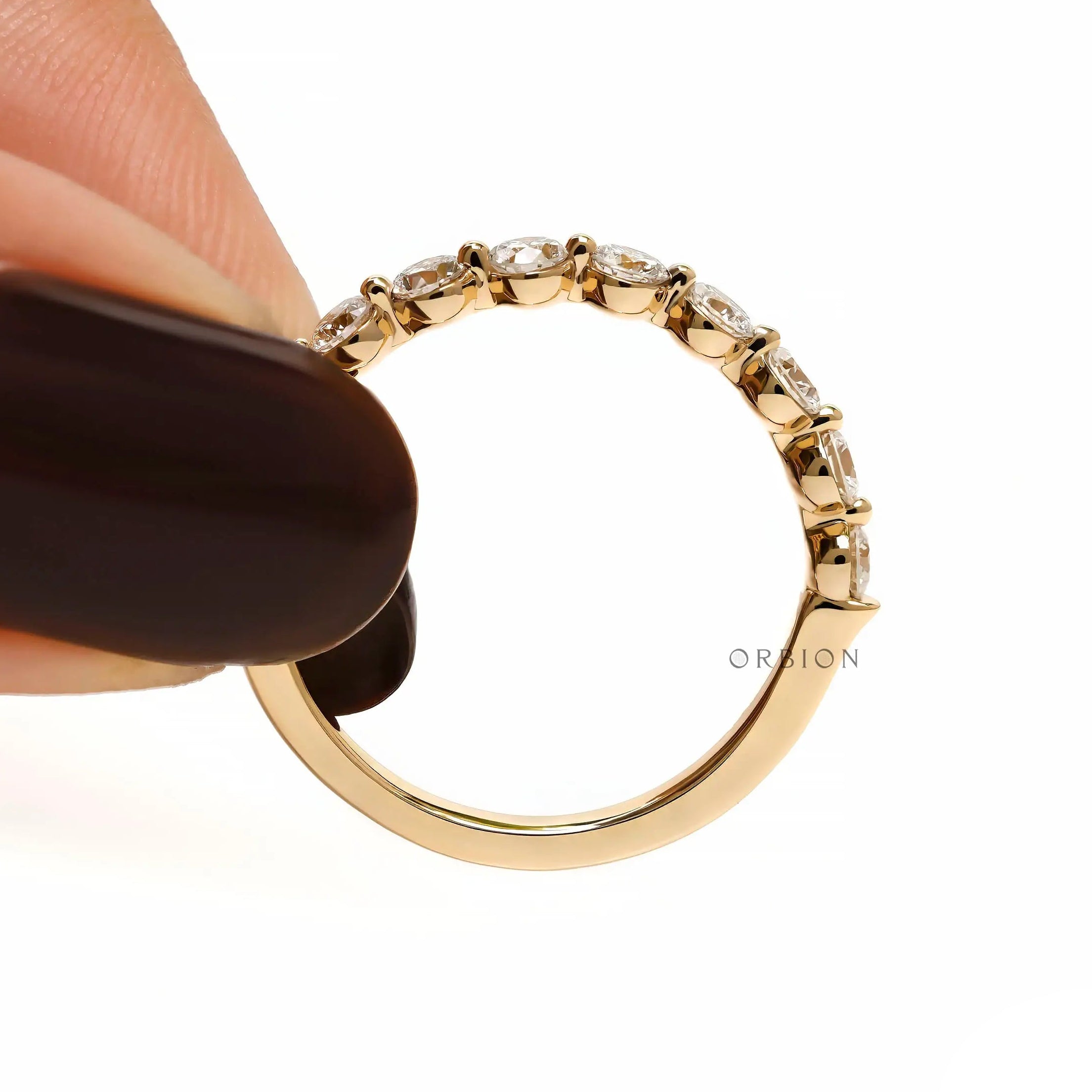 Held side view of round lab diamond shared prong half eternity wedding band