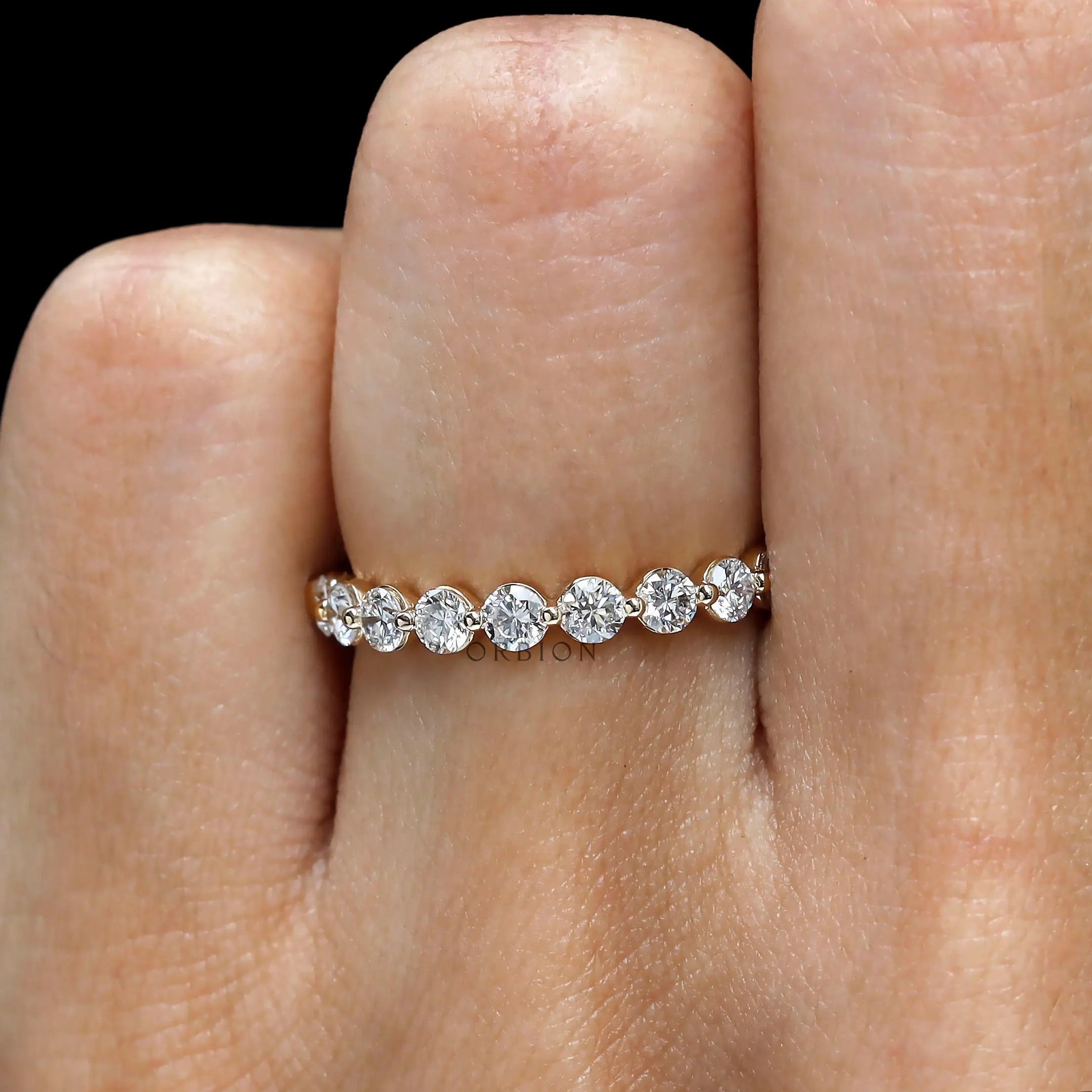 Close-up hand view of round lab diamond shared prong half eternity band
