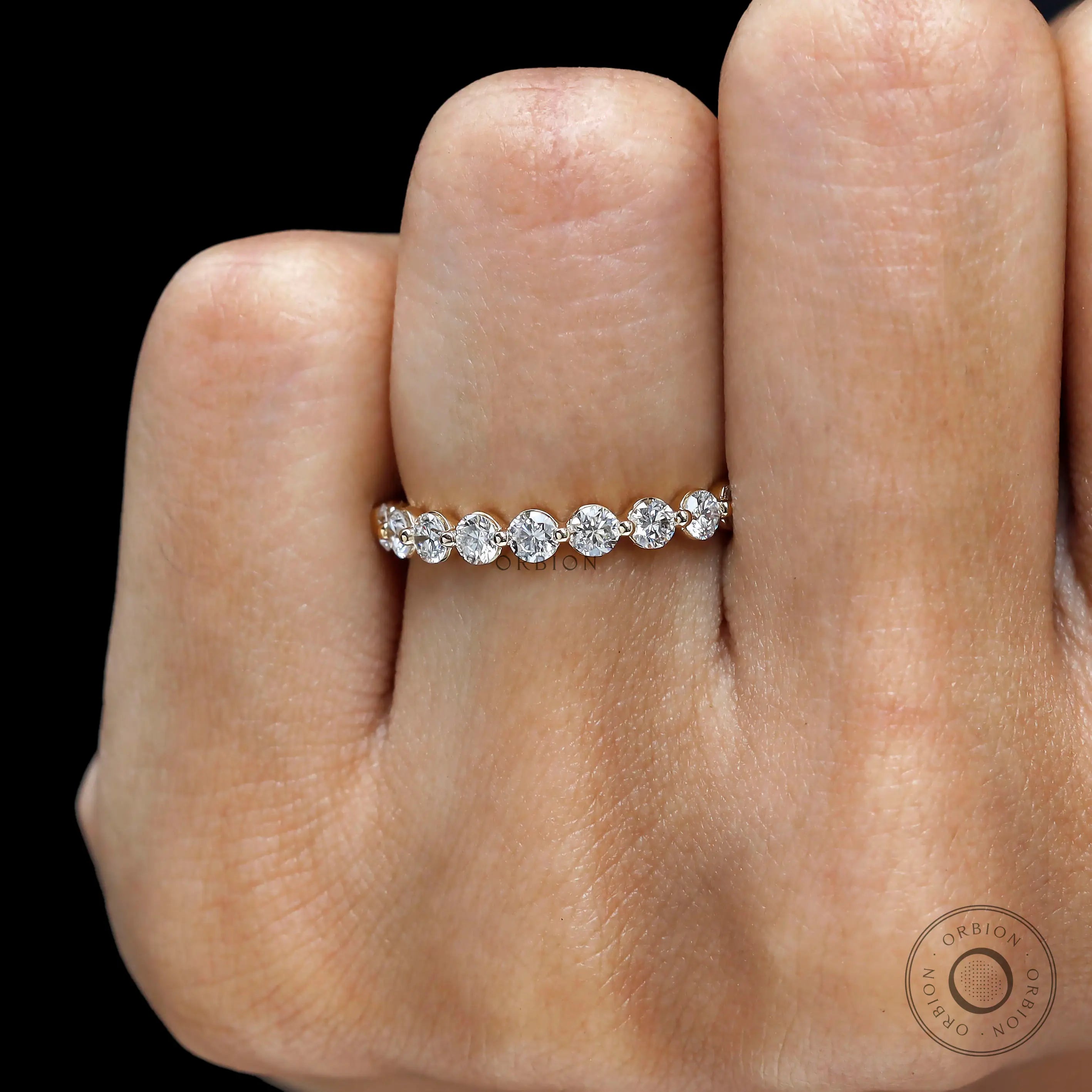 Close-up hand view of round lab diamond shared prong half eternity band