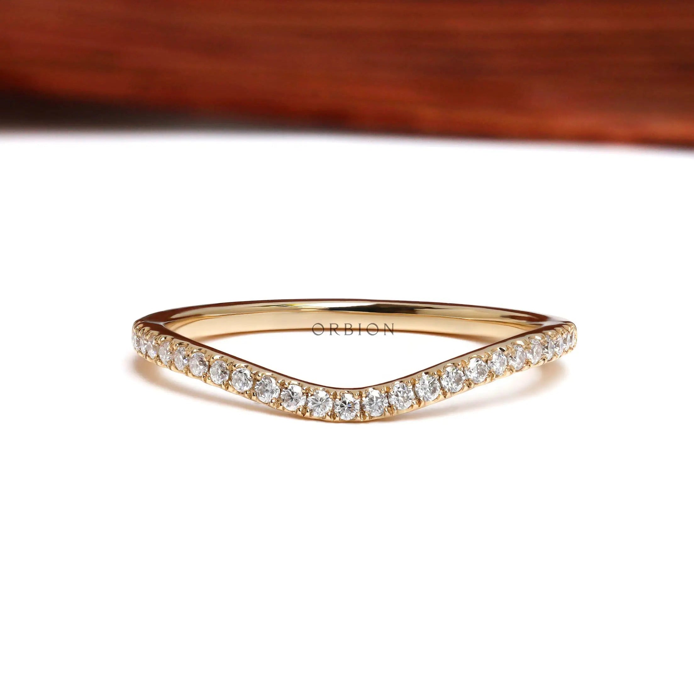 Front view of curved half eternity moissanite wedding band in yellow gold