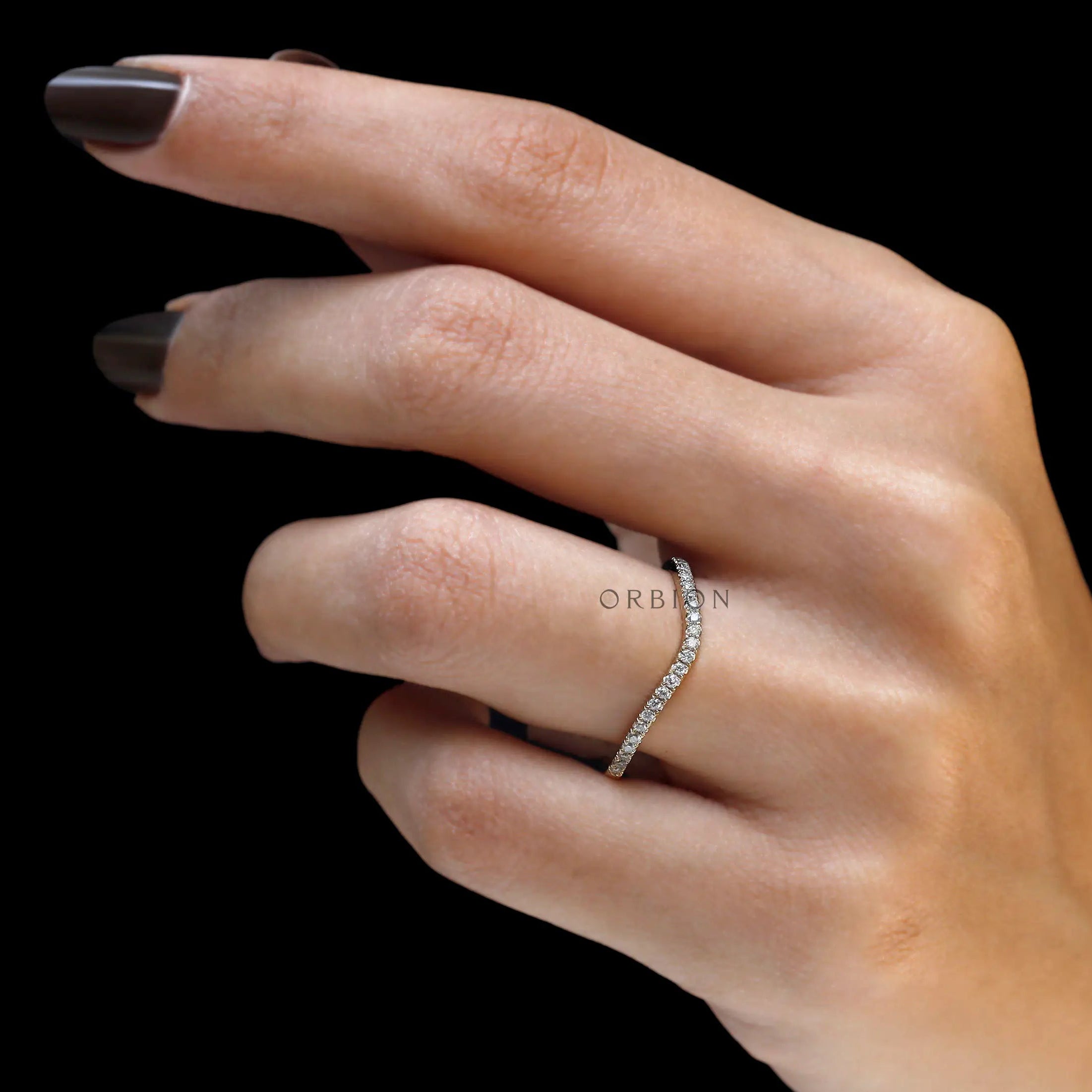 Hand model side view of curved moissanite wedding band
