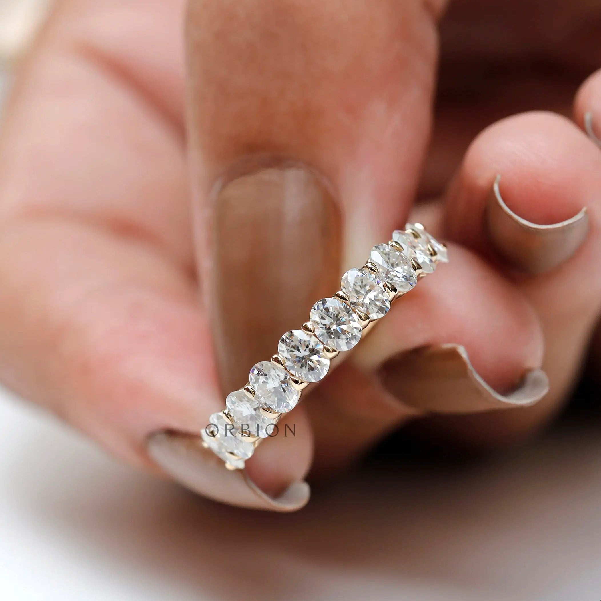Side profile of oval moissanite half eternity band in polished gold