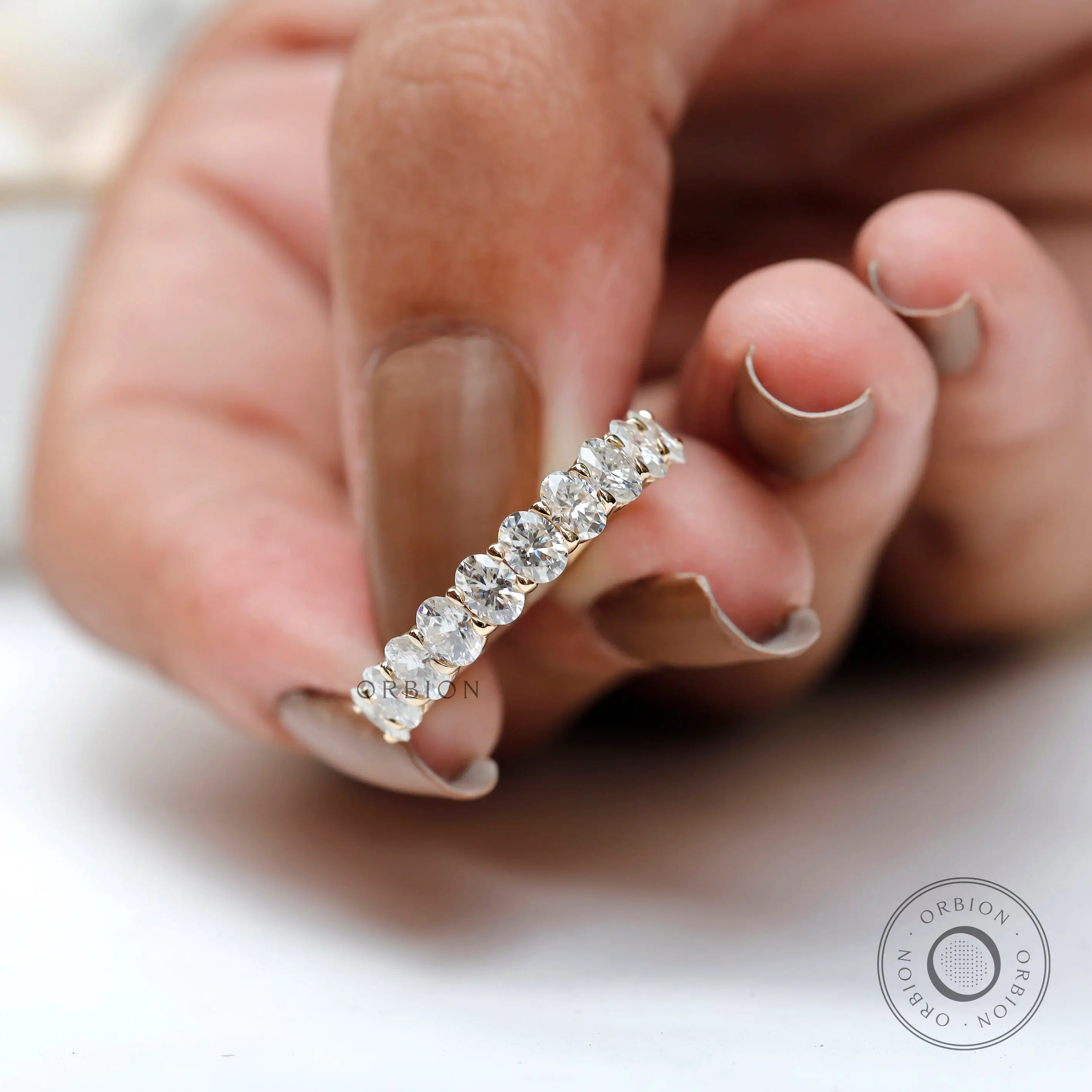 Side profile of oval moissanite half eternity band in polished gold