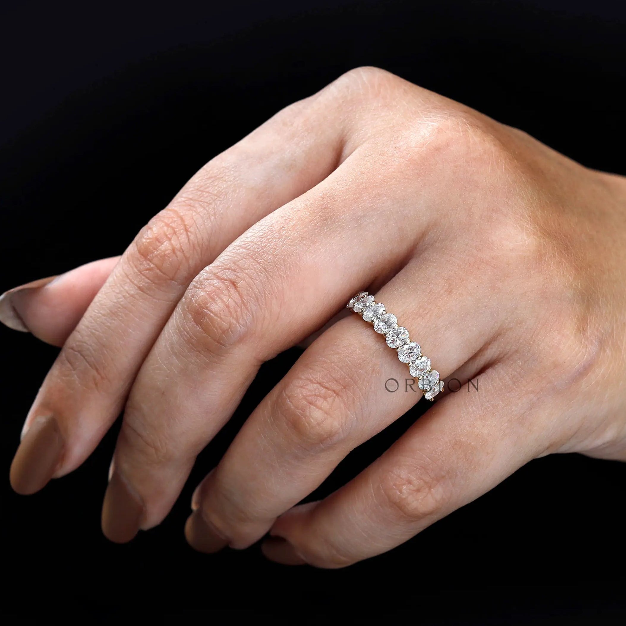 Stackable oval moissanite band on hand highlighting elongated stones