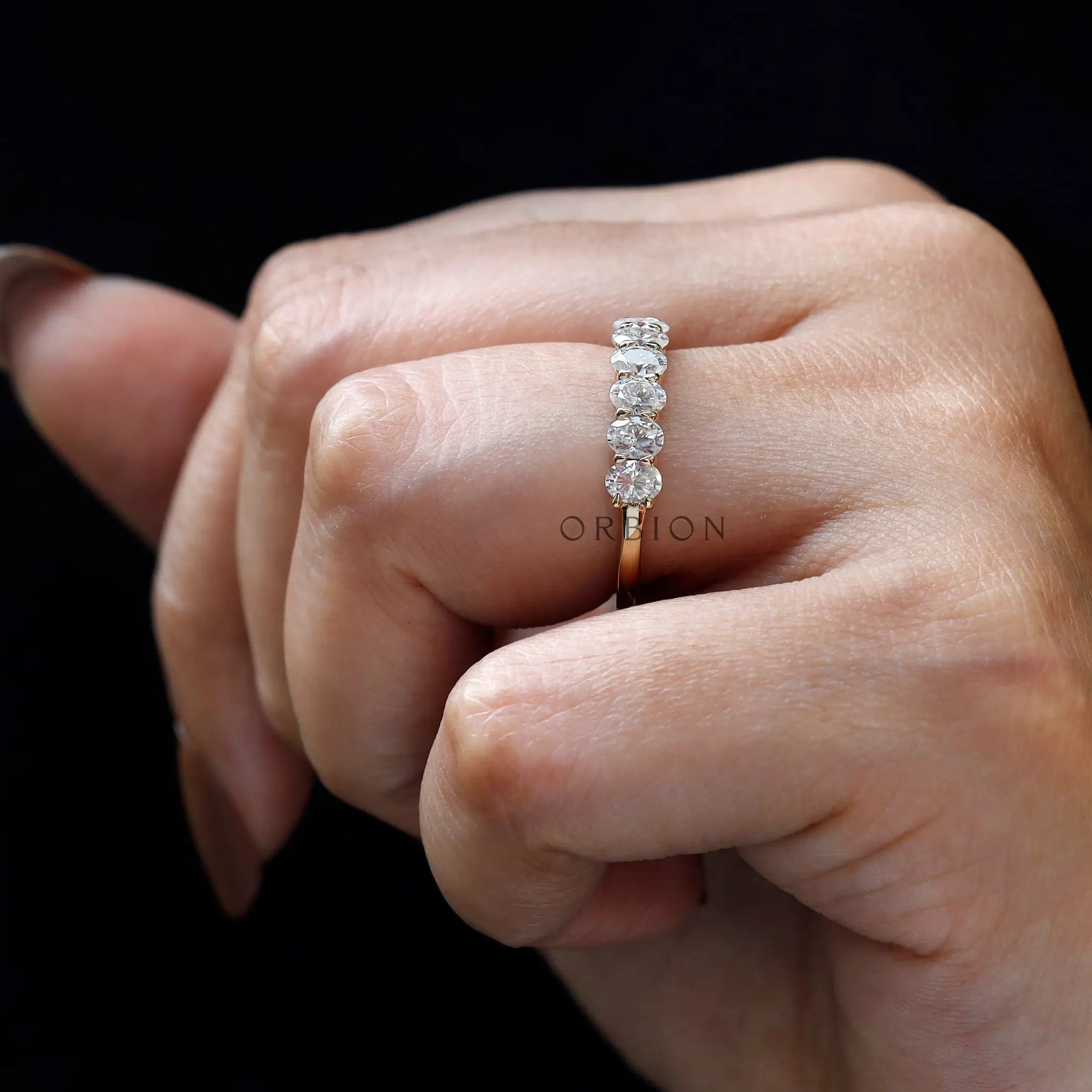 Oval moissanite half eternity band worn on finger close-up