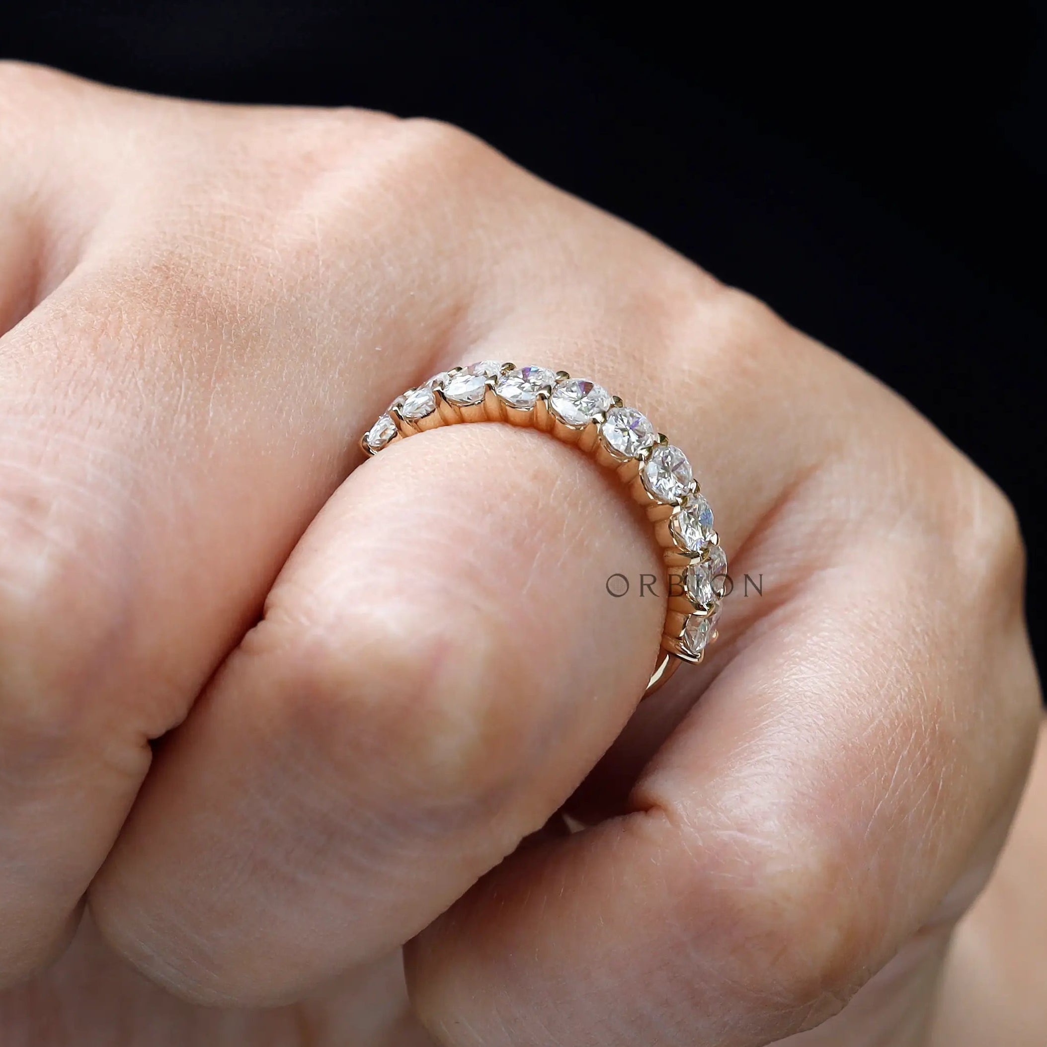 Elegant oval moissanite wedding band shown worn on hand