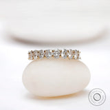 Oval moissanite half eternity band displayed on a smooth white stone