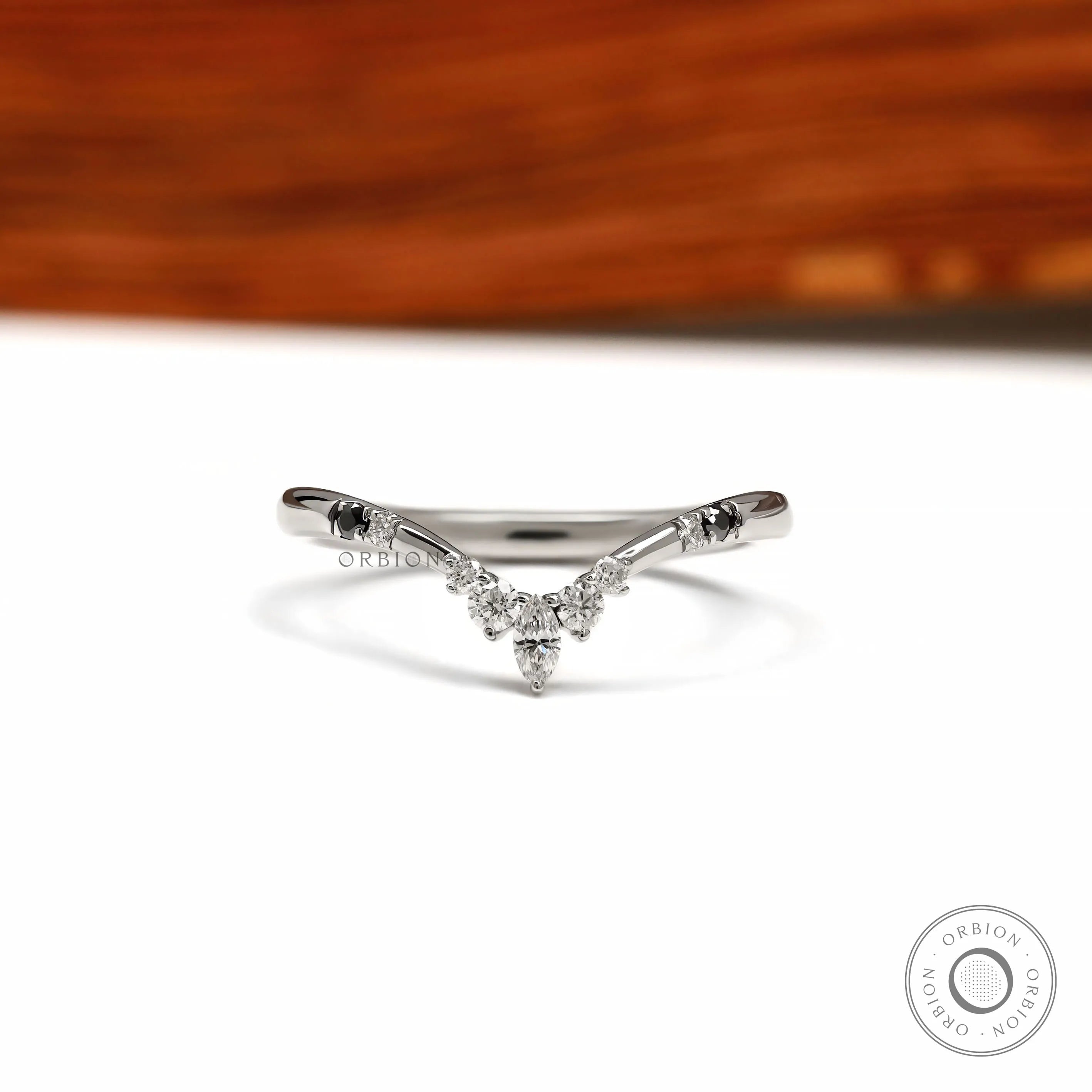Platinum chevron wedding band with V shaped wishbone design featuring black and white gemstones