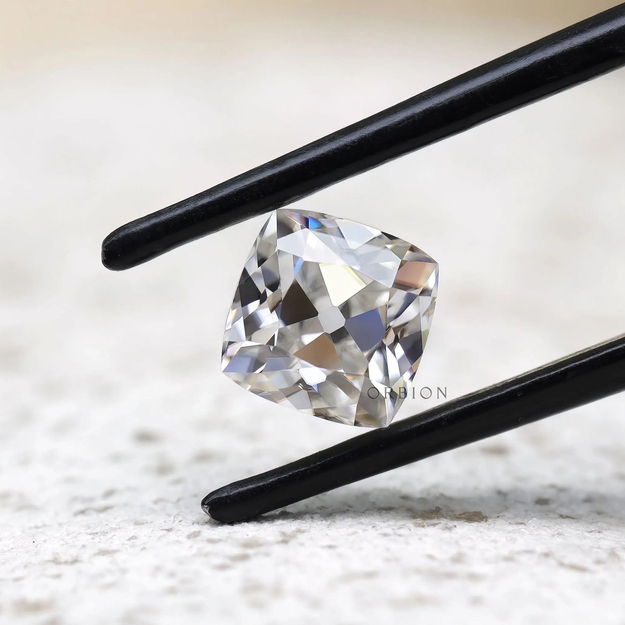Cushion Peruzzi cut moissanite held in tweezers