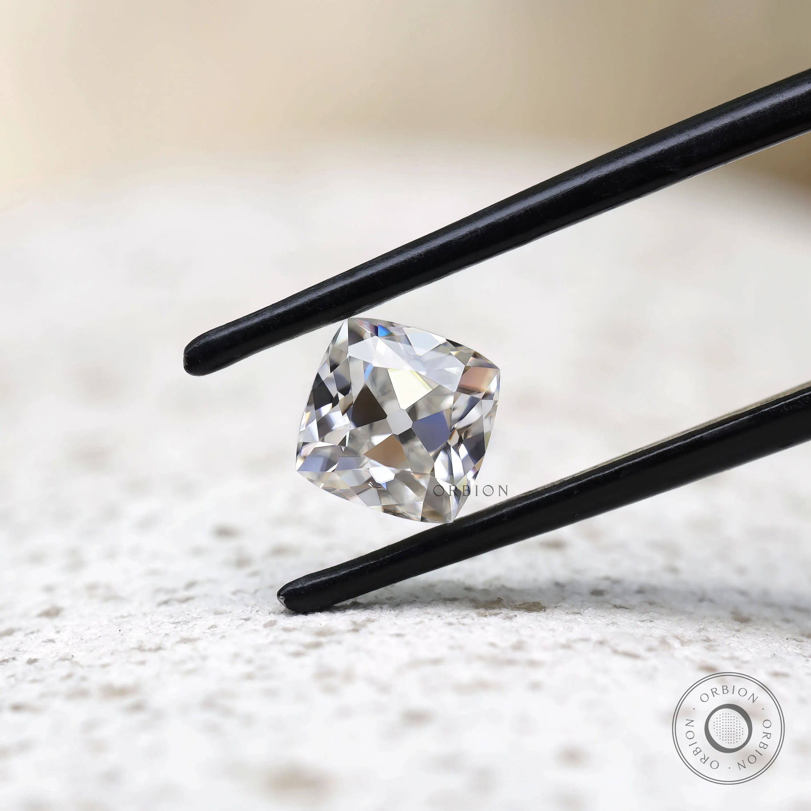 Cushion Peruzzi cut moissanite held in tweezers