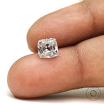 Cushion moissanite gemstone shown on fingertip