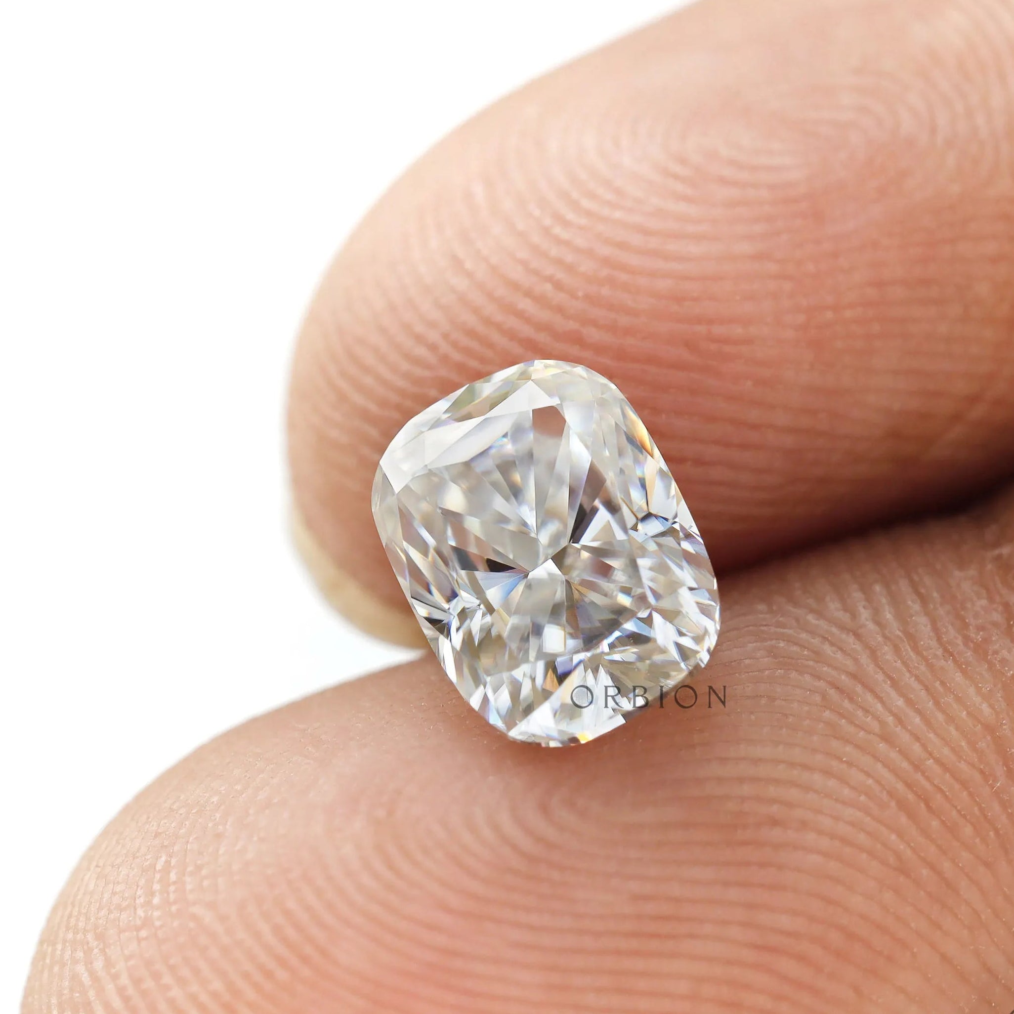 elongated cushion moissanite held on fingertip close view