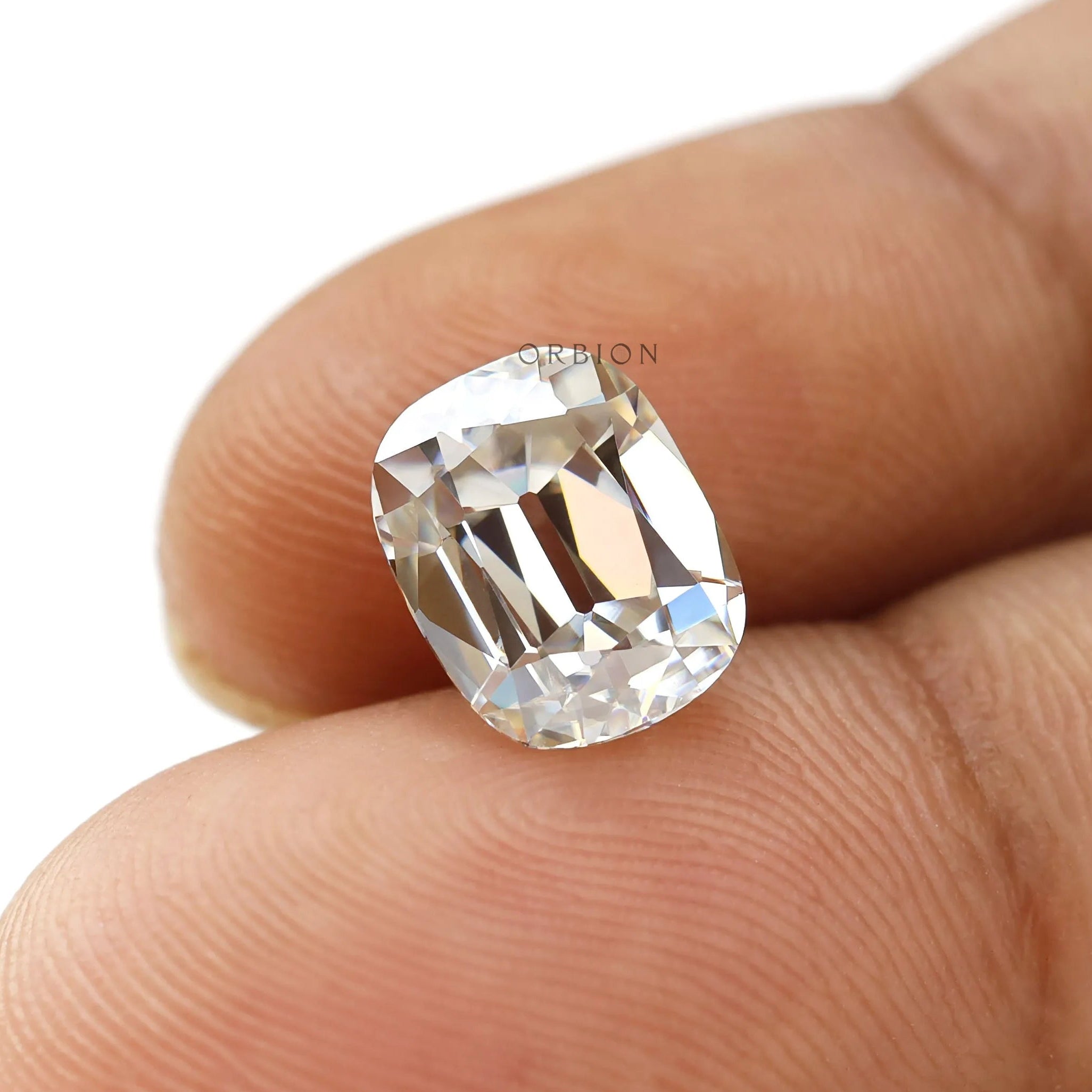 Moissanite Elongated Cushion Stone Held Between Fingers for Scale
