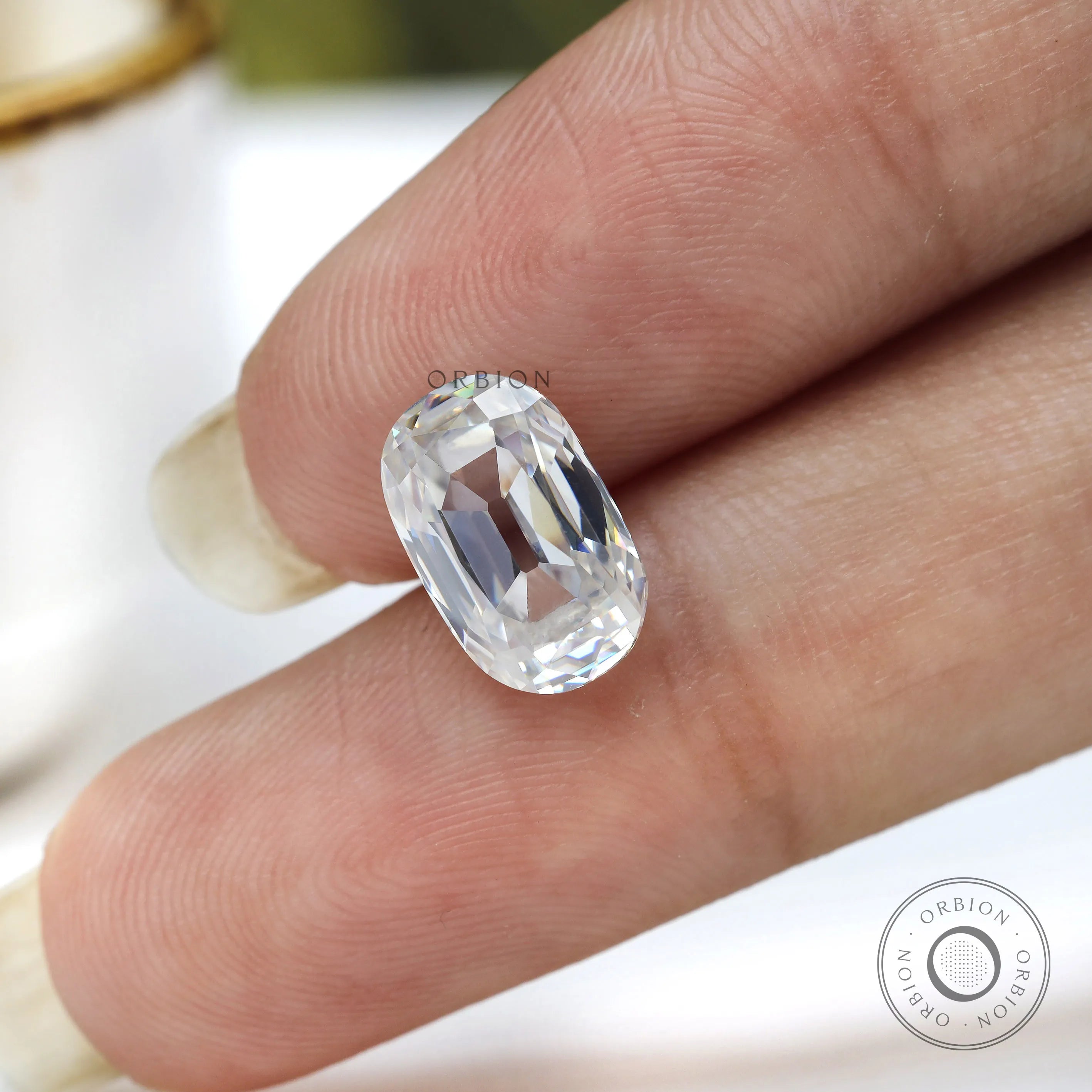 loose elongated cushion moissanite placed on fingertip close detail