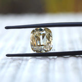 Elongated cushion old mine cut yellowish moissanite held in tweezers