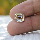 Yellowish moissanite held between fingers showing scale