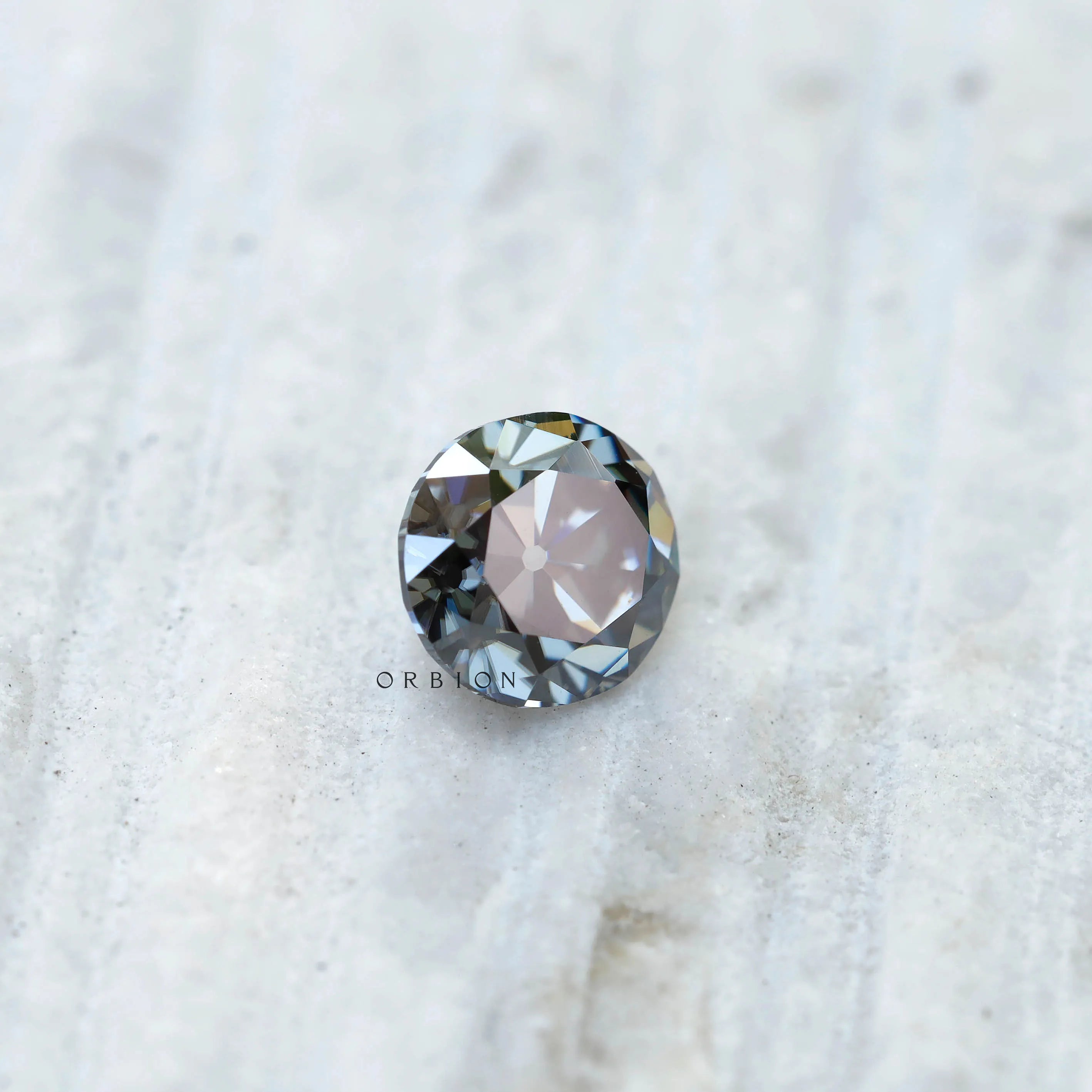 Side profile of grey round moissanite showing old European cut faceting