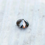 Grey round moissanite gemstone with soft reflective facets on surface