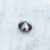 Grey round moissanite gemstone with soft reflective facets on surface
