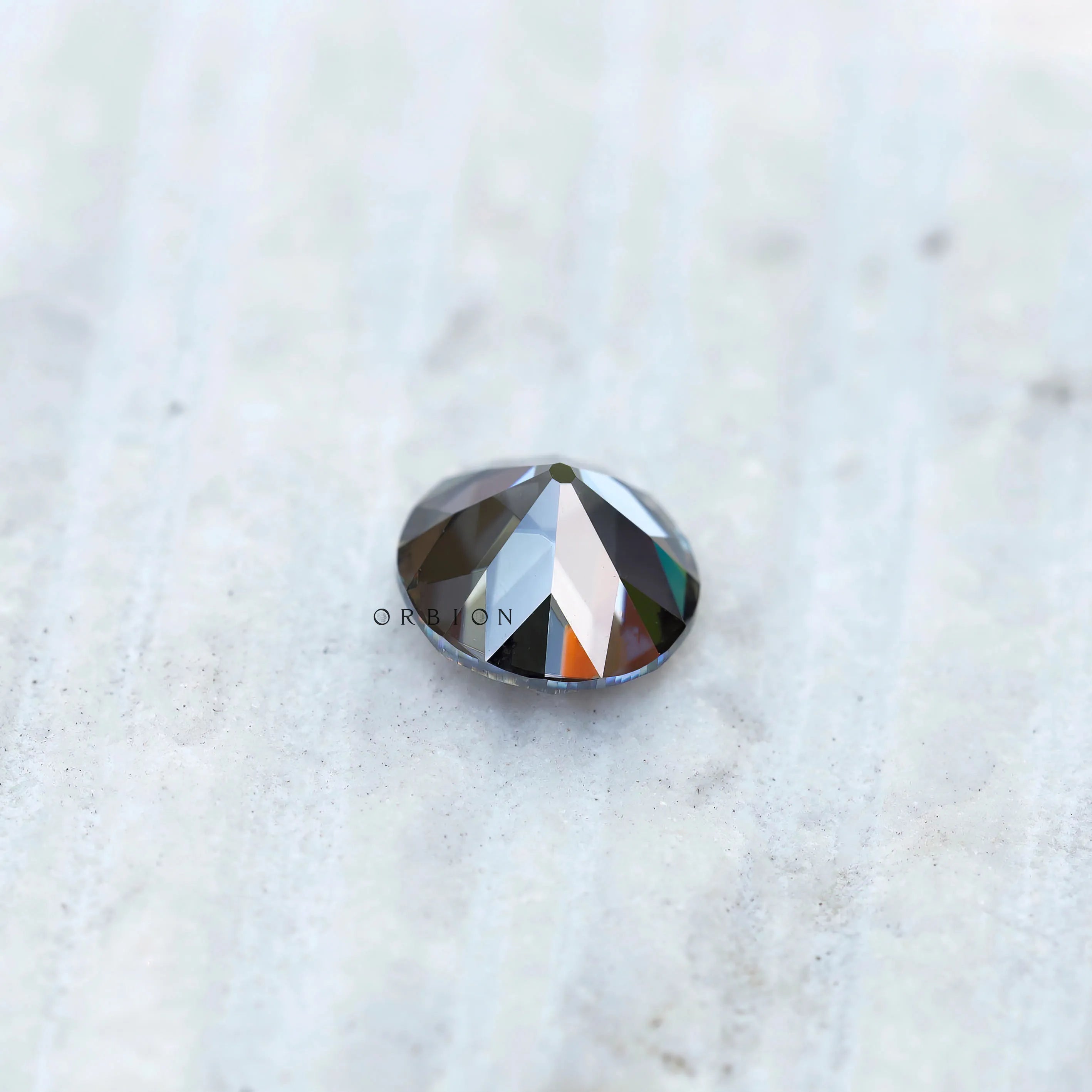 Grey round moissanite gemstone with soft reflective facets on surface