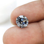 1.50 ct old european cut round dark grey moissanite loose stone, held on a fingertip