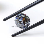 1.50 ct old european cut round dark grey moissanite loose stone, tilted in tweezers