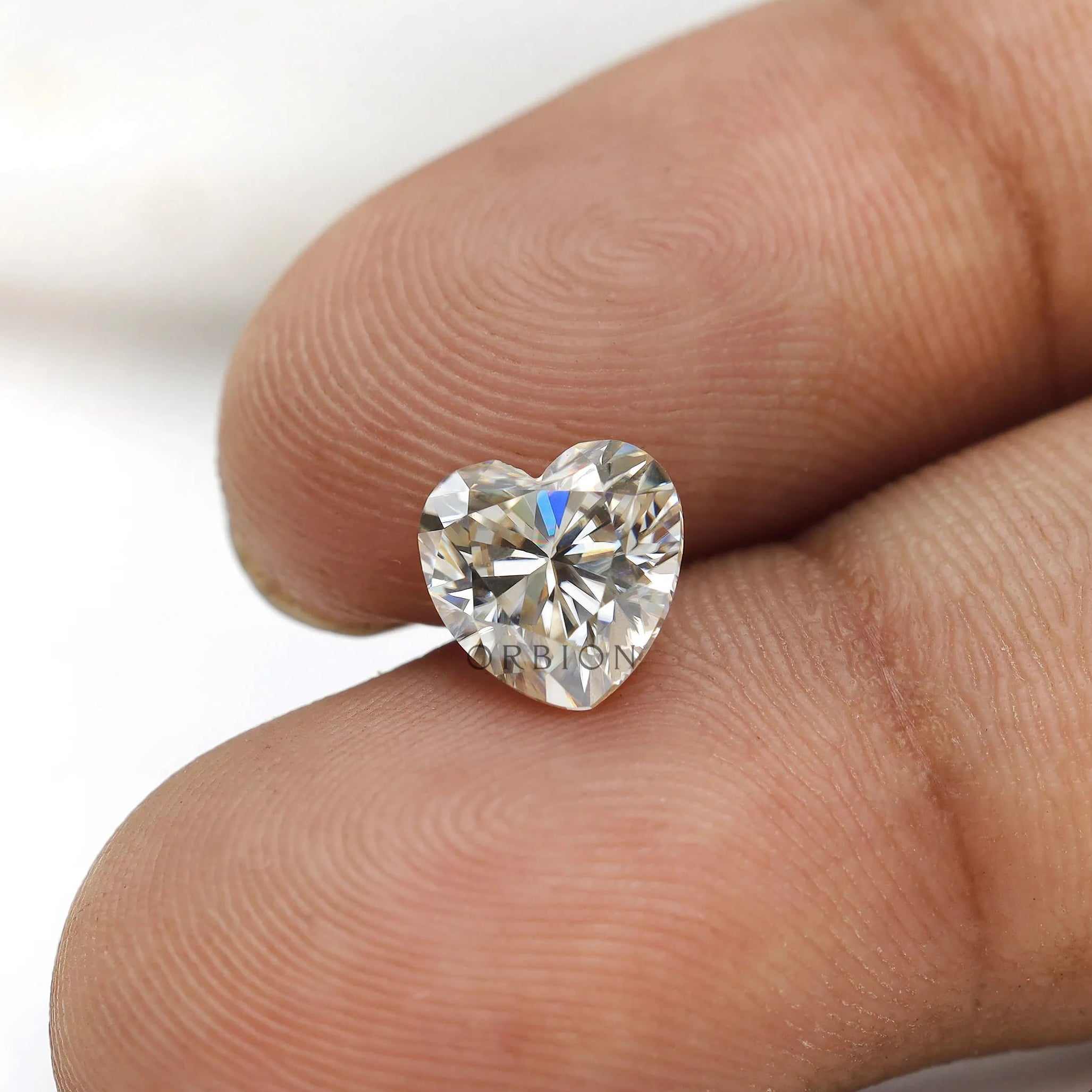 1.50 ct heart shape GHI moissanite loose stone, face up on a fingertip