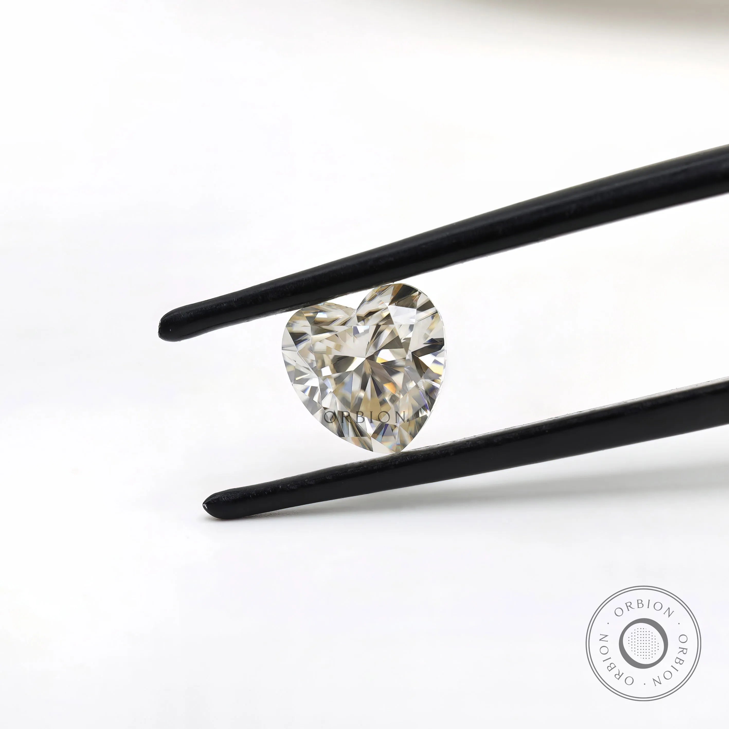 Heart shape GHI moissanite held with tweezers front view