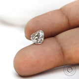Loose heart moissanite placed on fingertip for size reference