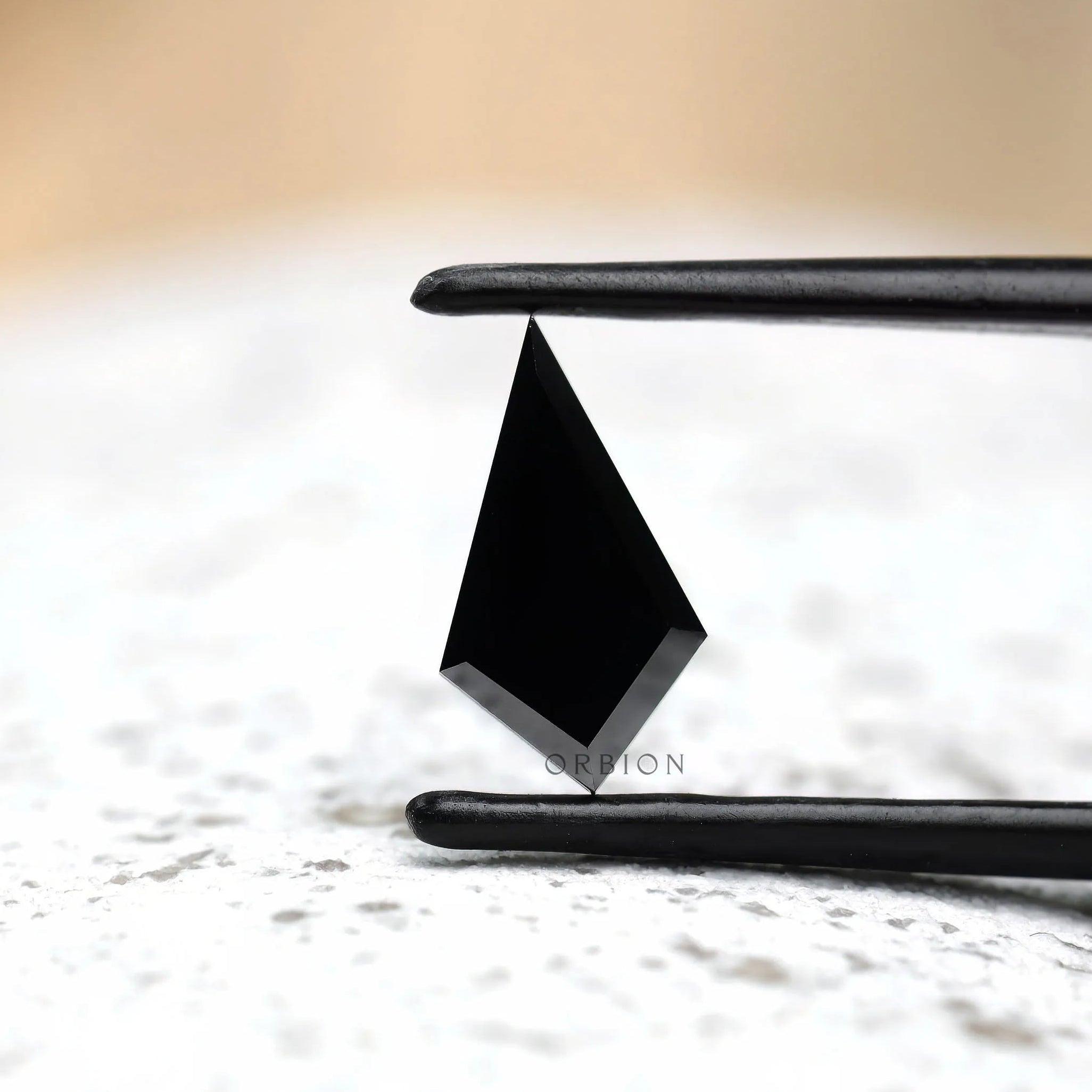 Kite shaped black moissanite with reflective surface close up
