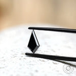 Kite cut black moissanite held in tweezers side angle
