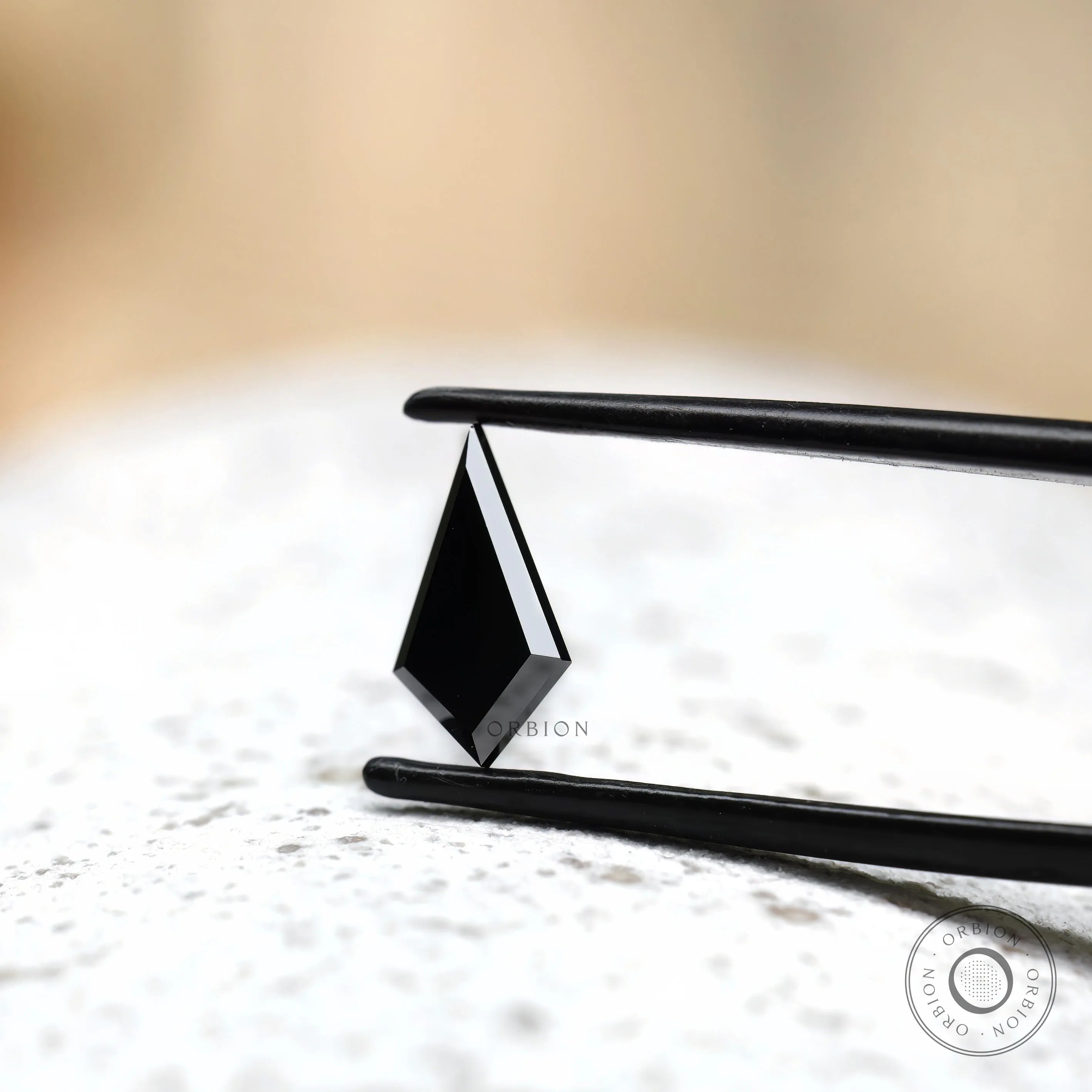 Kite cut black moissanite held in tweezers side angle