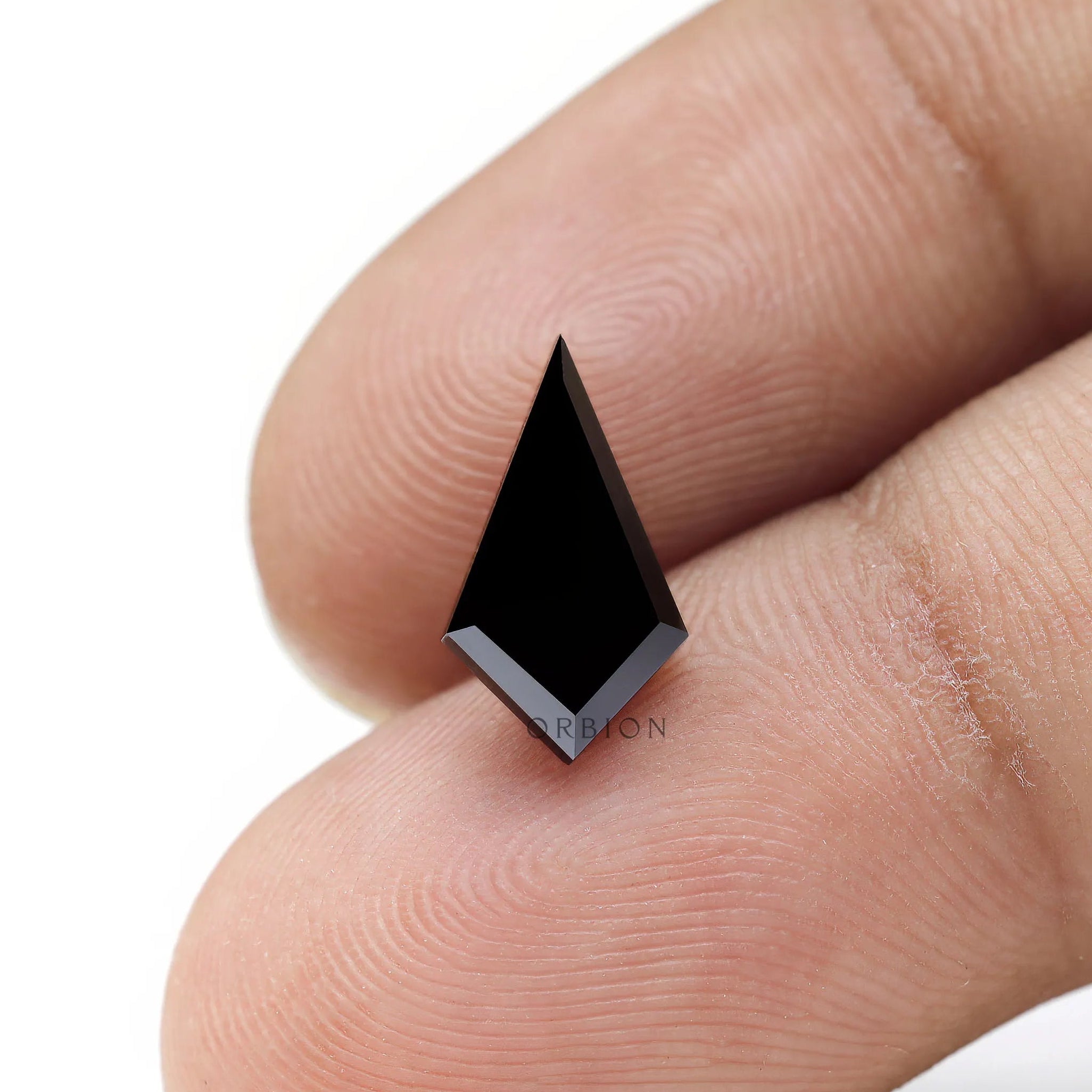 Loose kite moissanite displayed on fingertip for size reference