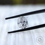 Oval moissanite gemstone held in tweezers front view