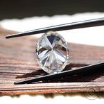 large oval moissanite held in tweezers showing proportions
