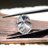 large oval moissanite held in tweezers showing proportions