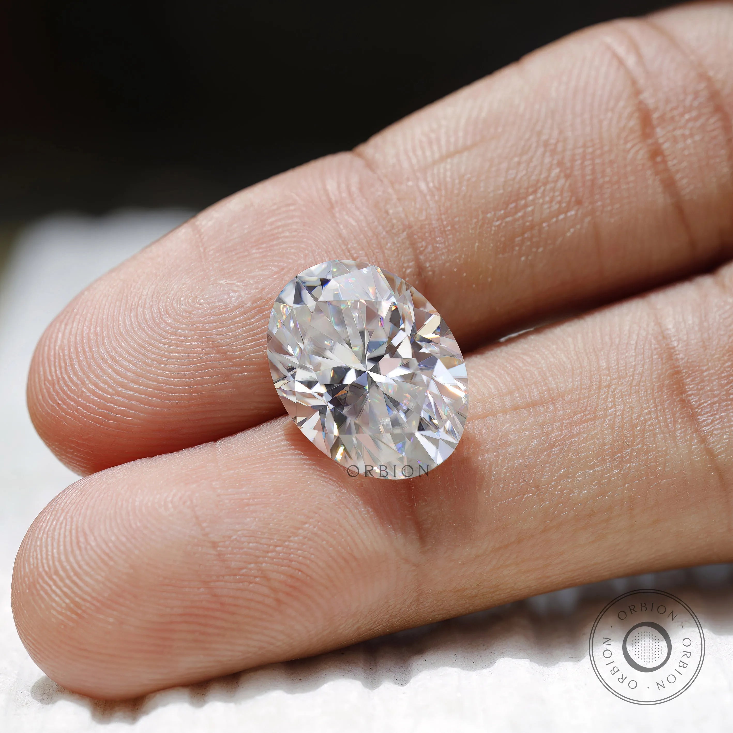 oval moissanite placed on fingertip for reference