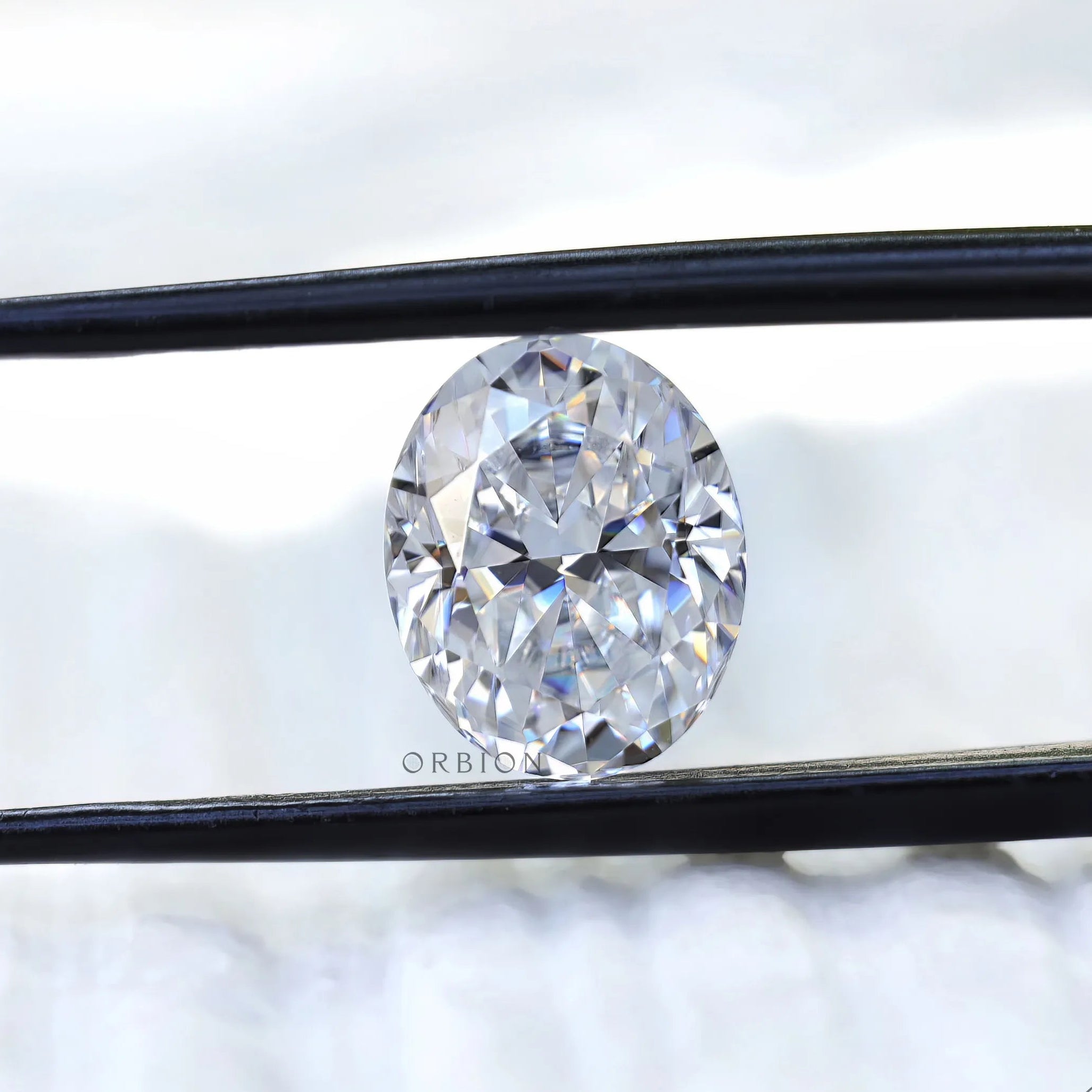 Oval crushed ice cut moissanite held with tweezers close view