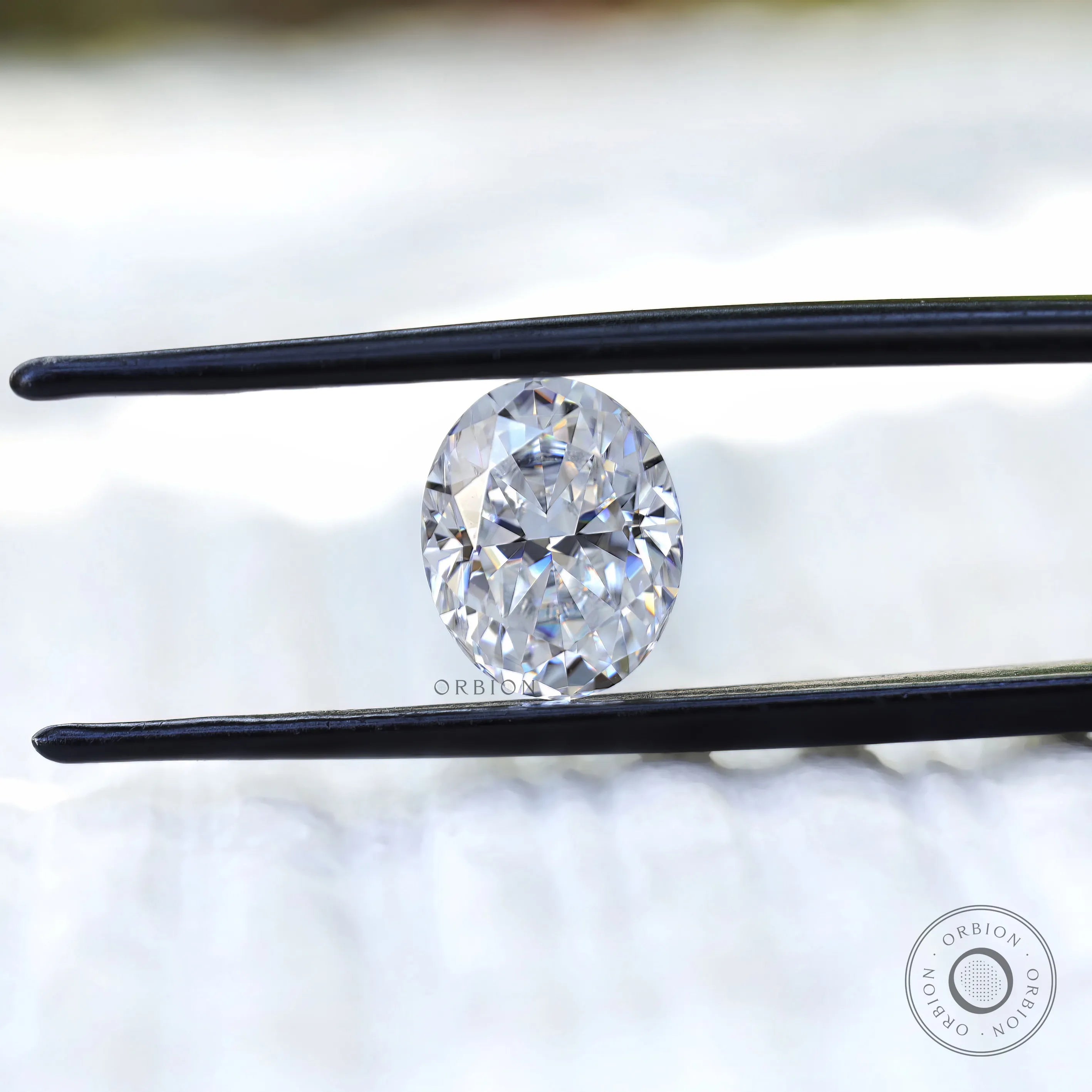Oval crushed ice cut moissanite held with tweezers close view