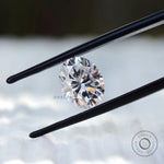 Oval moissanite gemstone held in tweezers front angle