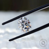 Oval moissanite gemstone held in tweezers front angle