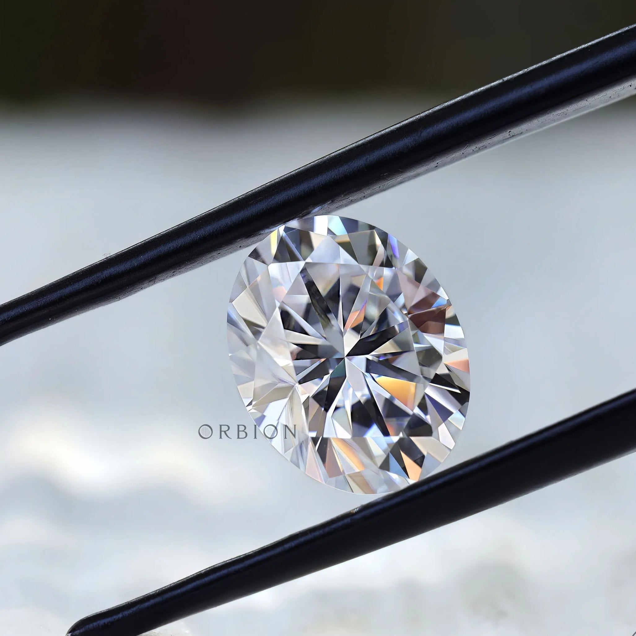 Oval moissanite gemstone held in tweezers front angle