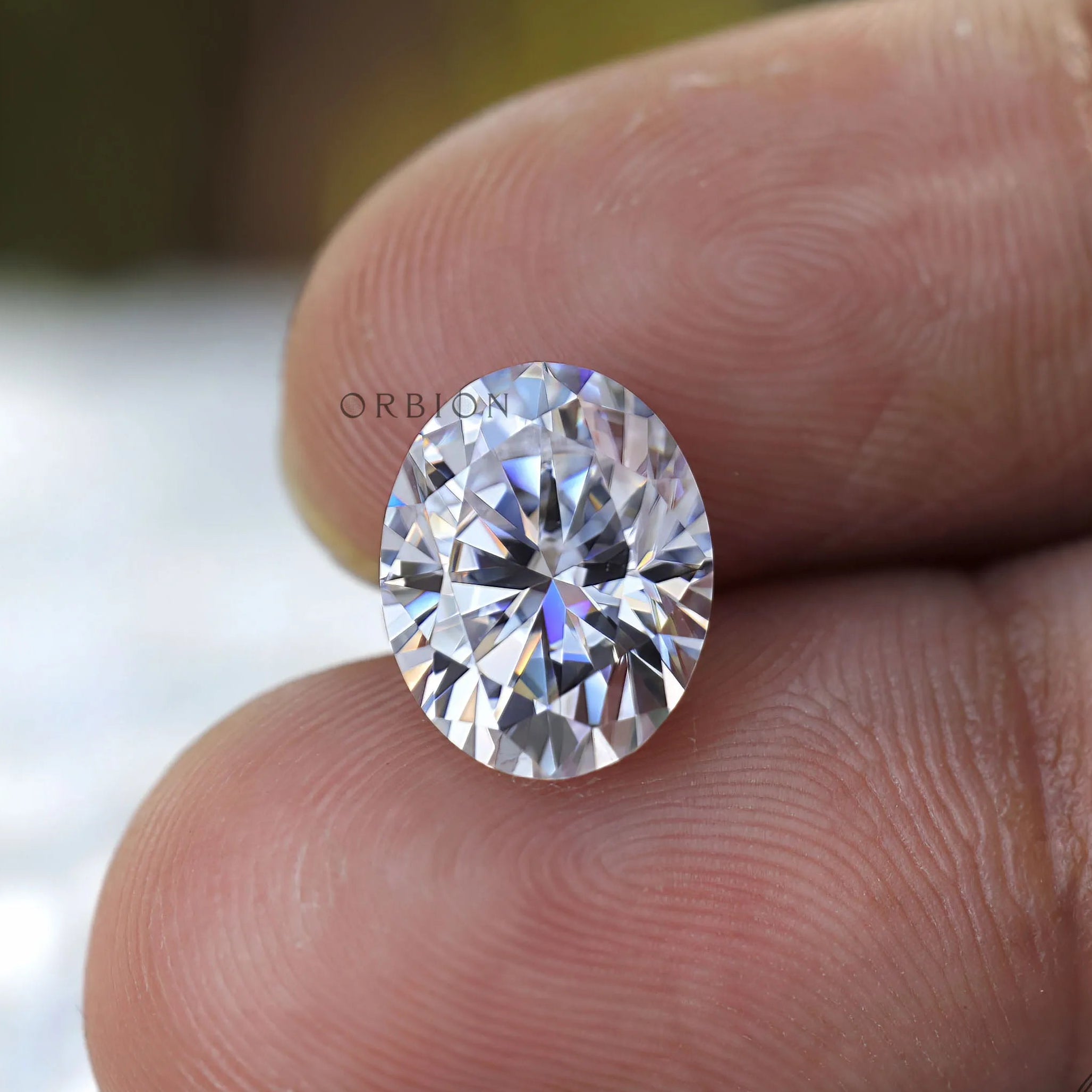 Oval cut moissanite on fingertip scale reference