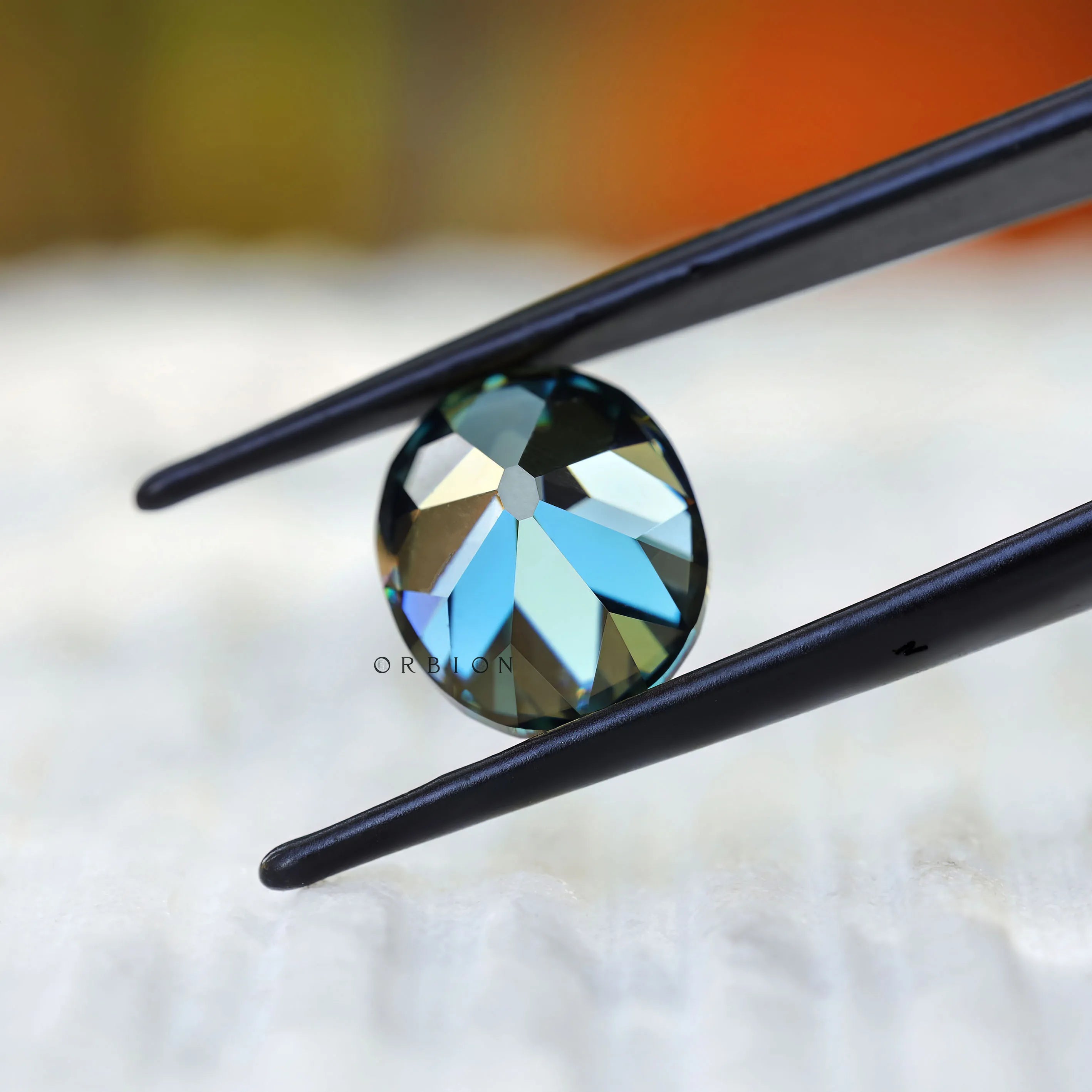 Dark green oval moissanite held in tweezers close view