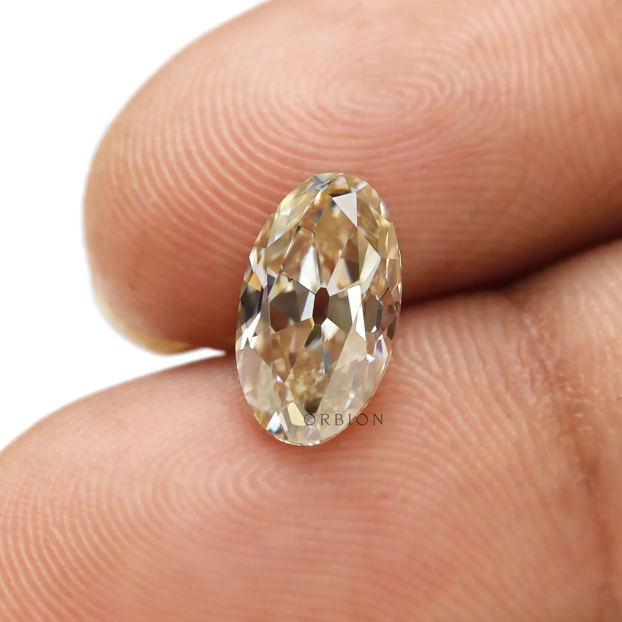 Close-up oval light champagne moissanite on fingertip