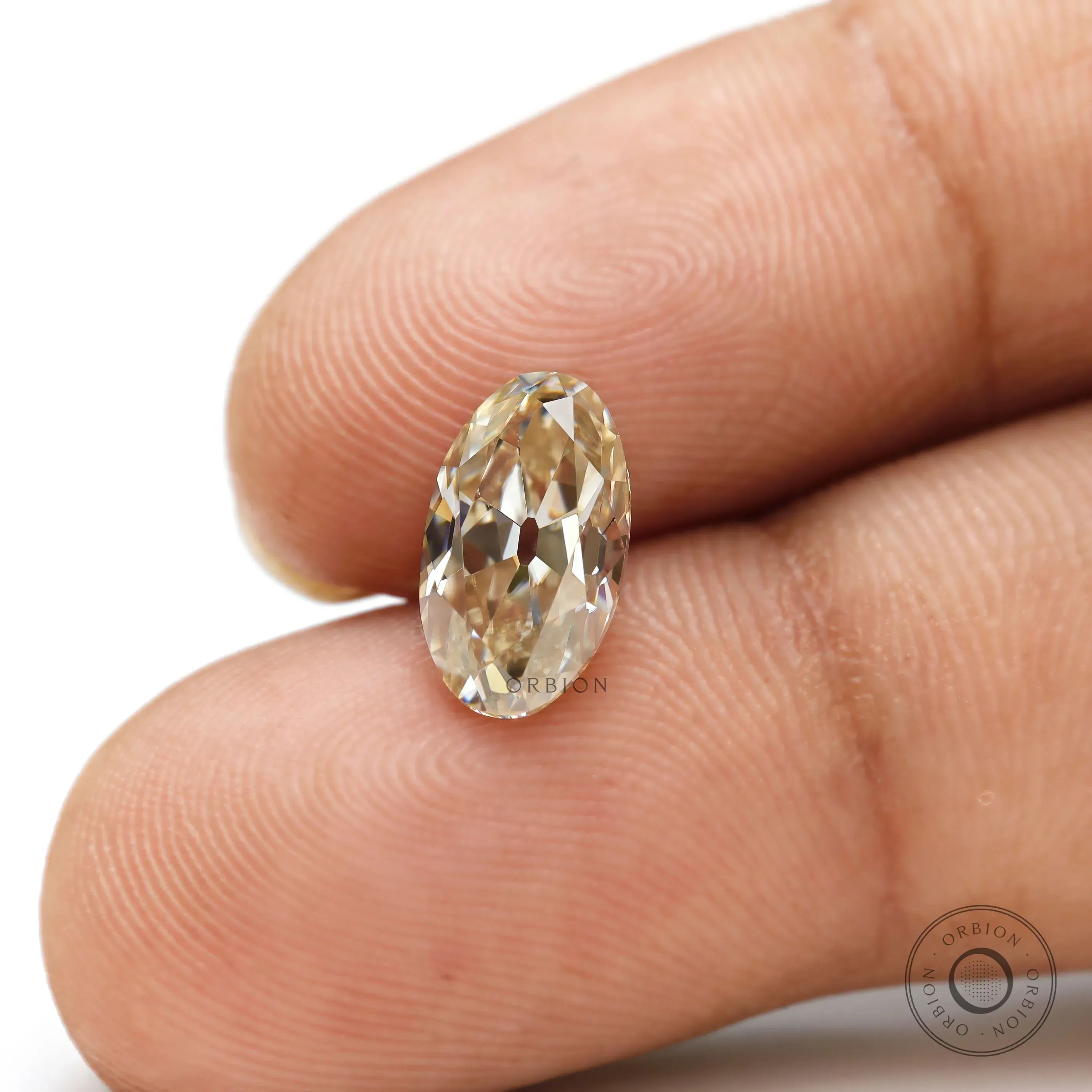 Close-up oval light champagne moissanite on fingertip