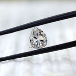 Front view of pear old mine cut moissanite in tweezers