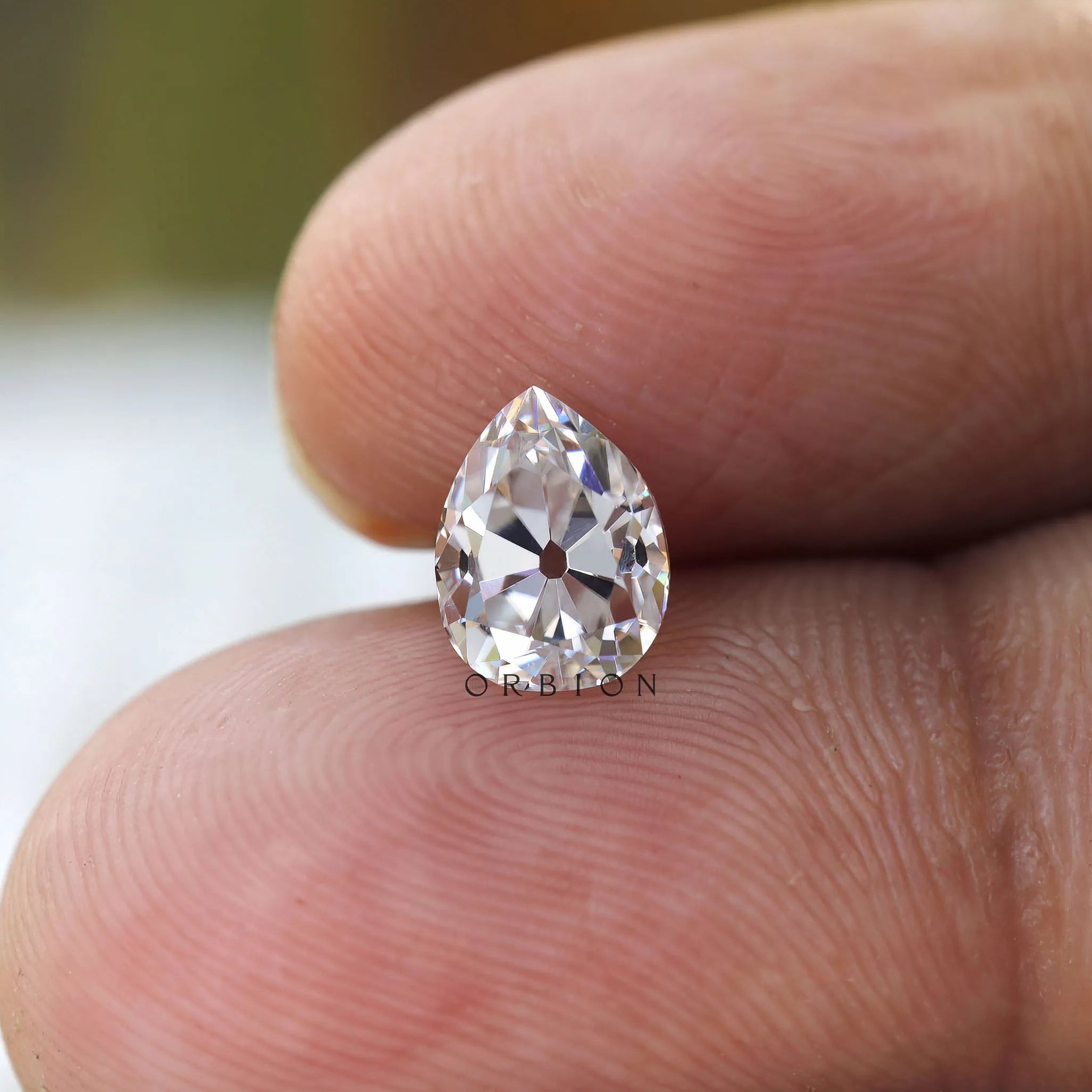 Finger scale view of pear moissanite size reference