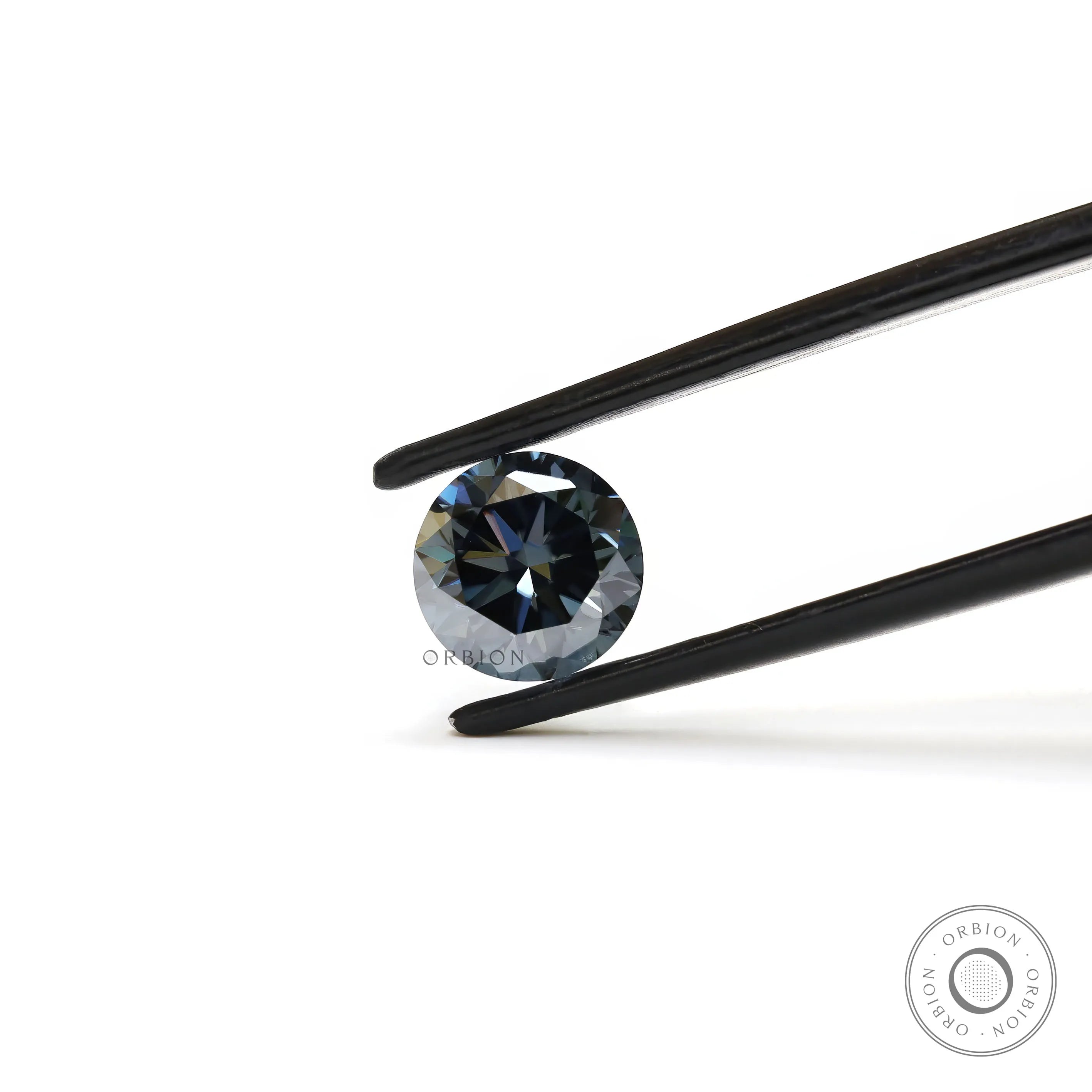 Dark grey round moissanite gemstone held in tweezers with sharp brilliant facets