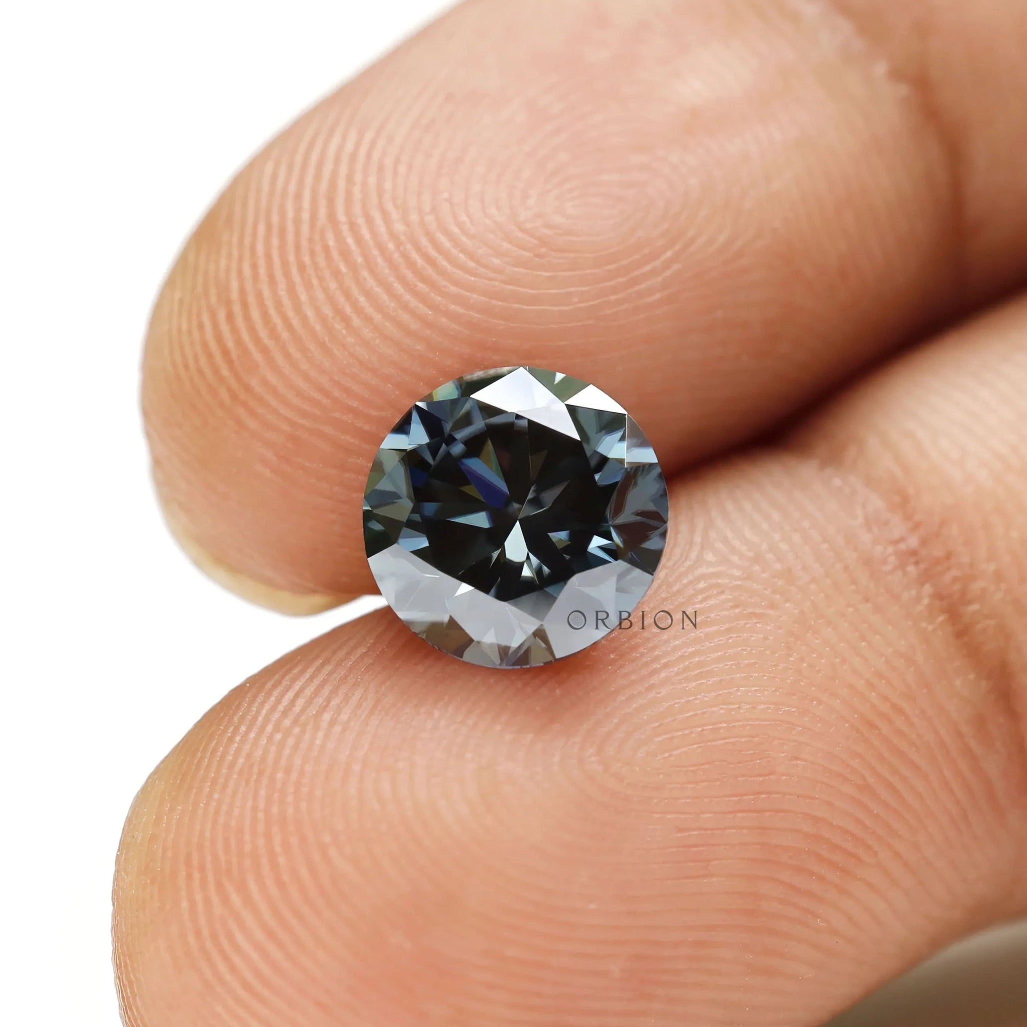 Round brilliant cut dark grey moissanite gemstone placed on surface